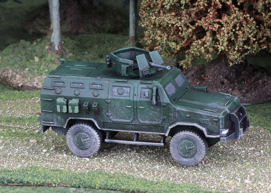 15mm scale model of Ukrainian Kozak armored vehicle in green, detailed and weathered, displayed outdoors on terrain with trees and bushes background