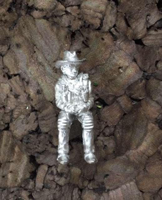 28mm Modern Wild Timmy unpainted miniature figure of a seated helicopter pilot on textured surface