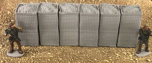 Six stacked 28mm modern Hesco barriers with two miniature soldier figures on dirt terrain background
