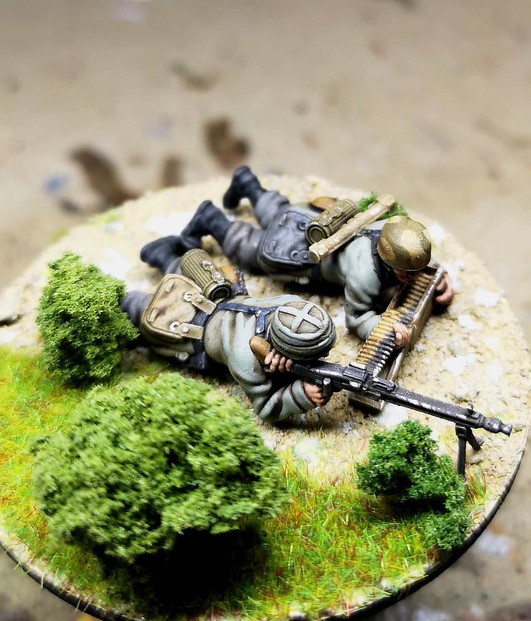 28mm German Fallschirmjager LMG 42 team miniatures in prone position with machine gun and ammunition on grassy battlefield base
