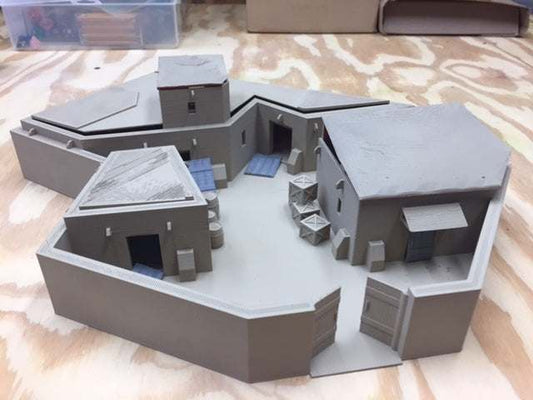 3D printed model of an Afghan compound with separate roofs and multiple buildings on a wooden surface